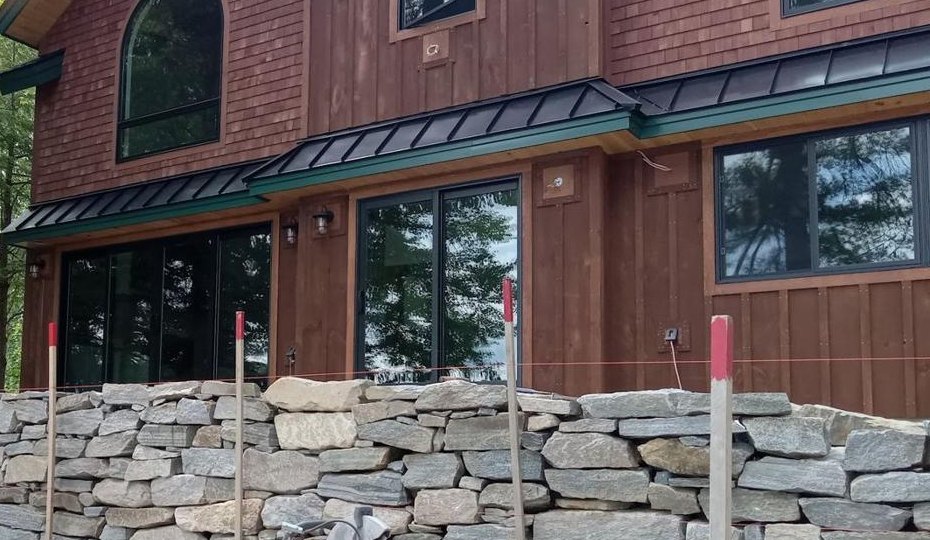 Dry laid fieldstone wall along a cedar lake house in New Hampshire