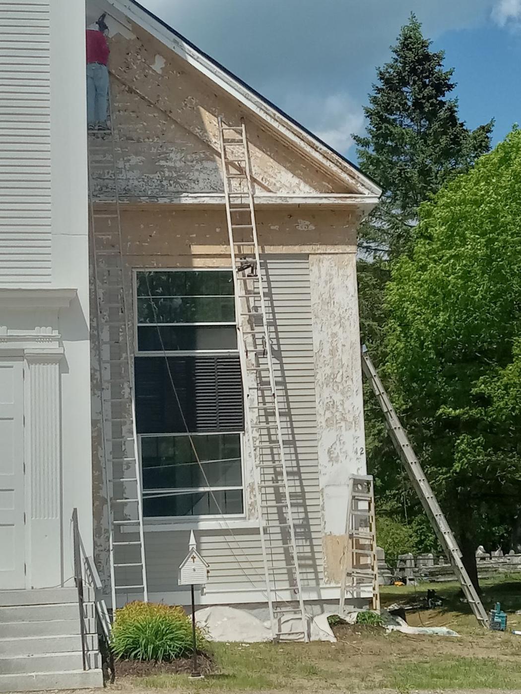 Exterior painting job on a two story house with ladders