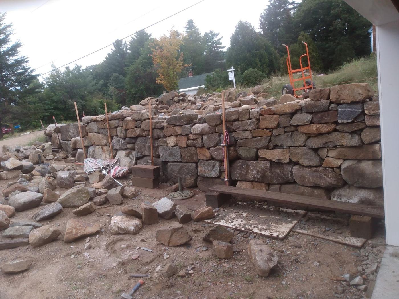 Tall fieldstone wall going up beside a lake property