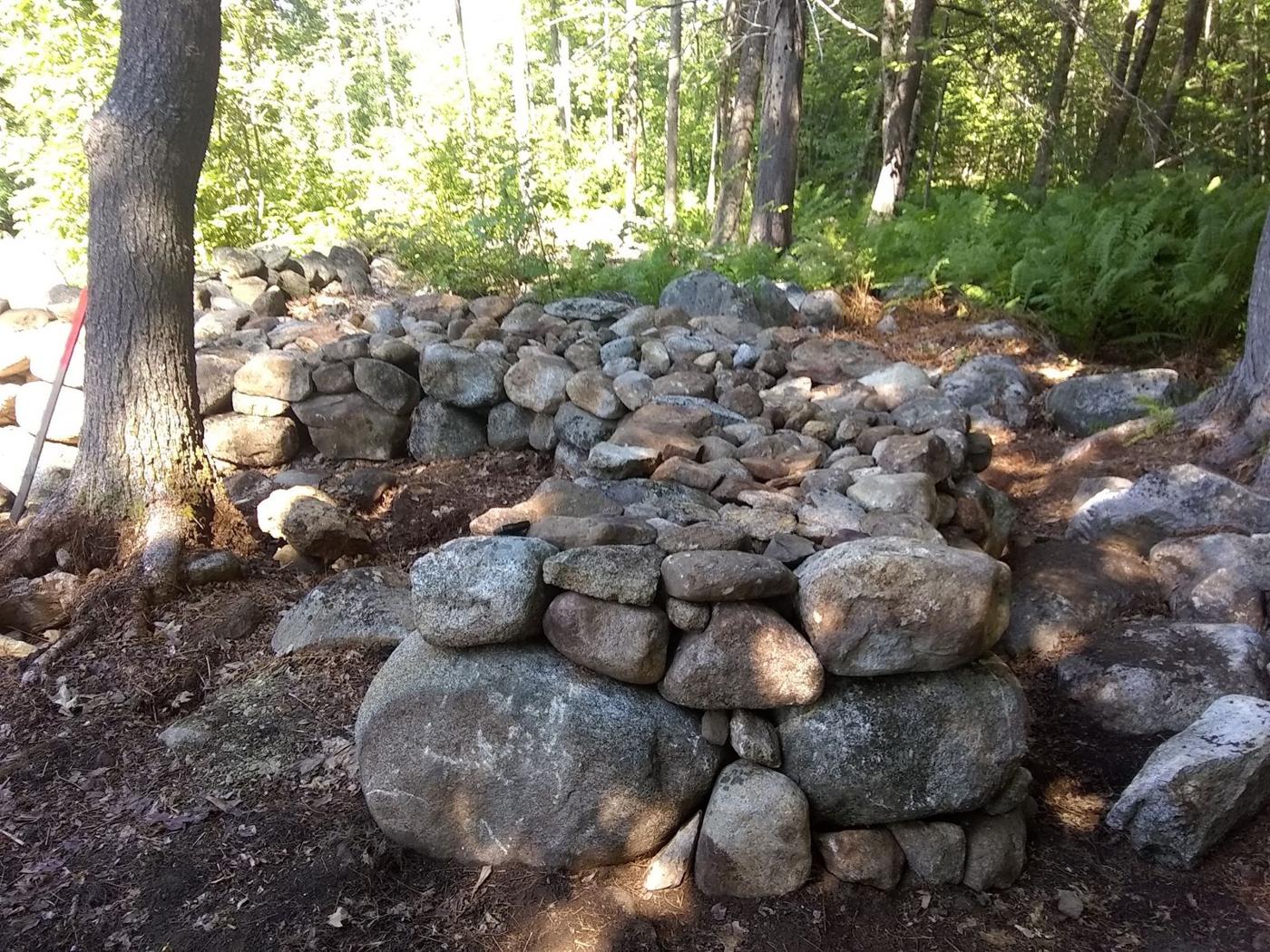 Boulder and fieldstone wall built through the woods among tall trees